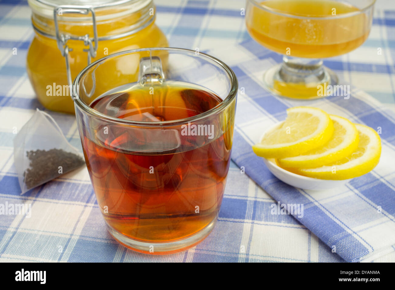 Tazza di tè con un vasetto di miele e le fette di limone sulla tavola. Pyramid sacchetto da tè nelle vicinanze. Foto Stock