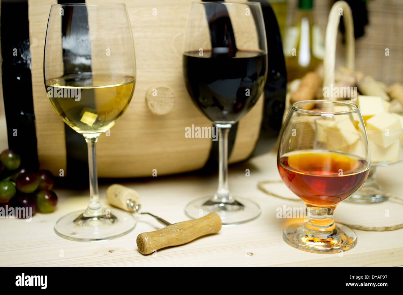 Vino rosso e bianco con gli occhiali, il brandy. Sullo sfondo di una canna  e tappi vino cestello, ciotola con il formaggio e una bottiglia Foto stock  - Alamy