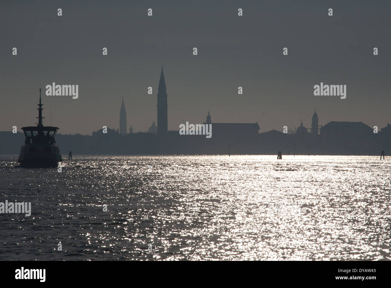 La laguna di Venezia con lo skyline della città in condizioni di luce solare intensa ed una barca in primo piano Foto Stock