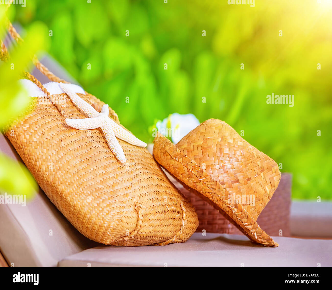 Estate accessori, cappello di paglia e la borsa decorata con starfish sdraiato sul lettino nel giardino sul beach resort Foto Stock