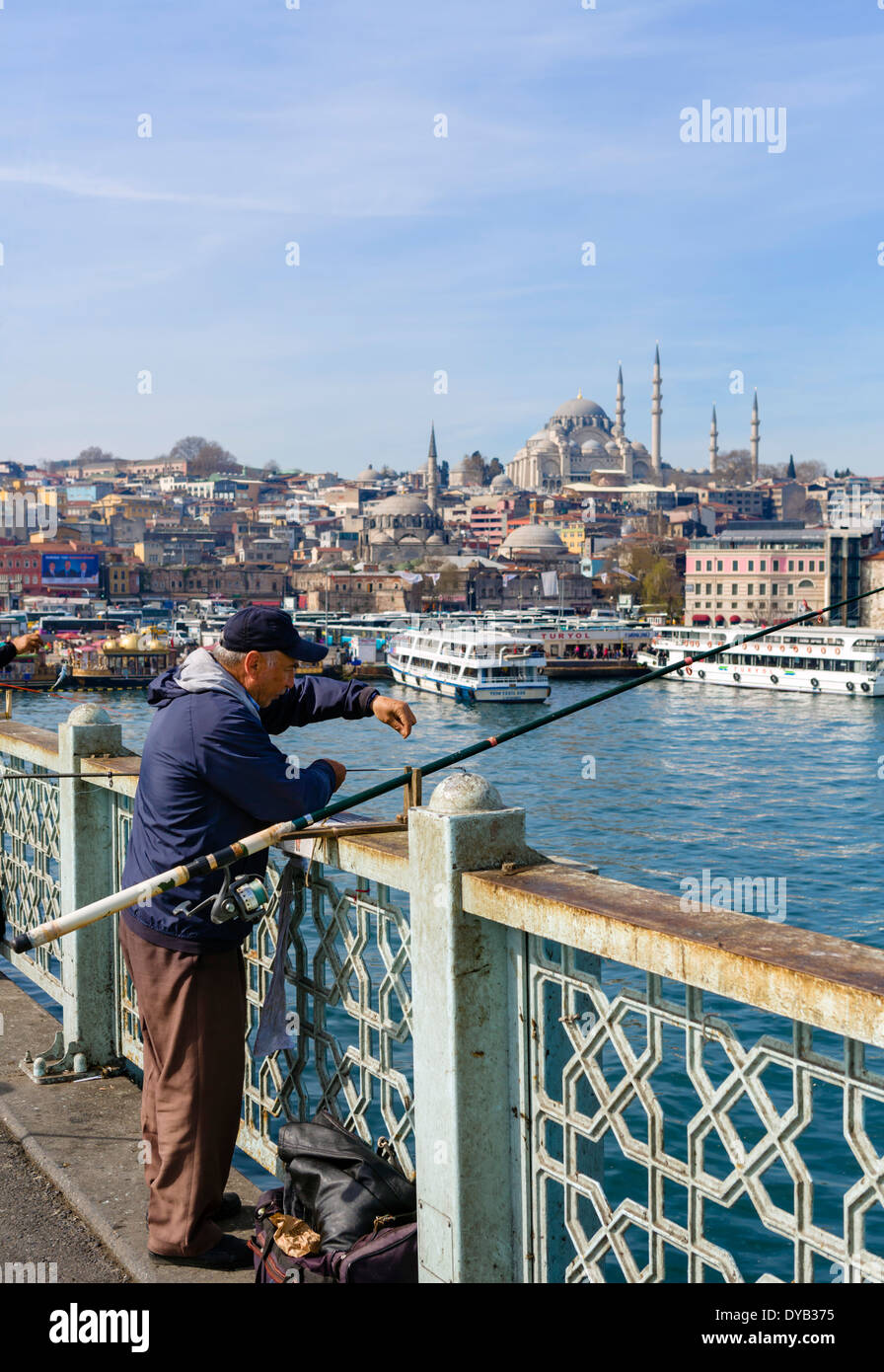 Il pescatore sul Ponte Galata con il quartiere Eminonu waterfront dietro, Istanbul, Turchia Foto Stock