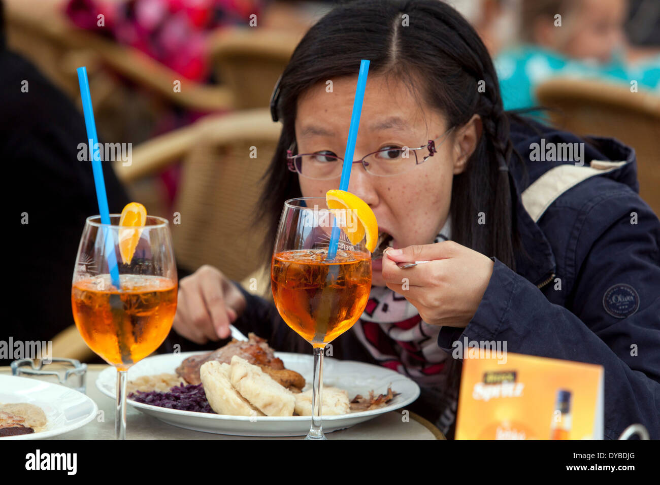 Asian tourist mangiare all'aperto cucina ceca tradizionale anatra, cavolo, e gnocchi Praga Repubblica Ceca Foto Stock