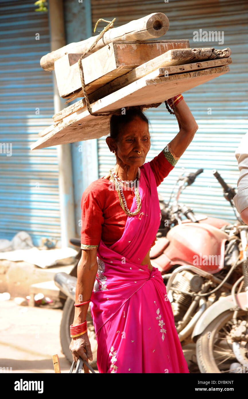 Delhi, India. Il 6 aprile 2014. Una signora anziana trasporta un carico pesante su una tipica stradina di Vecchia Delhi, India. Foto Stock