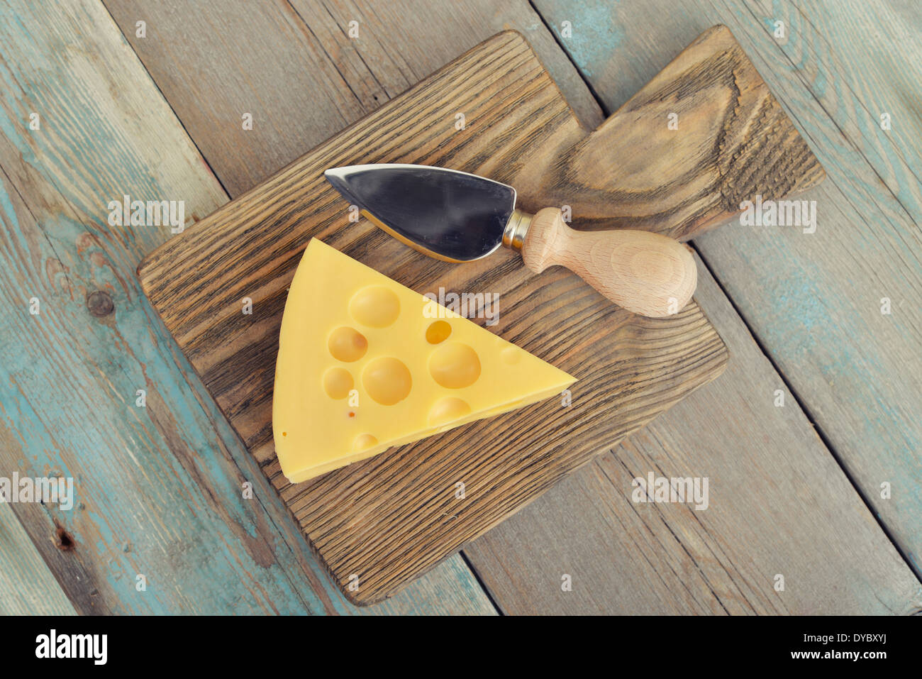 Formaggio con grandi fori e il coltello sul tagliere di legno Foto Stock