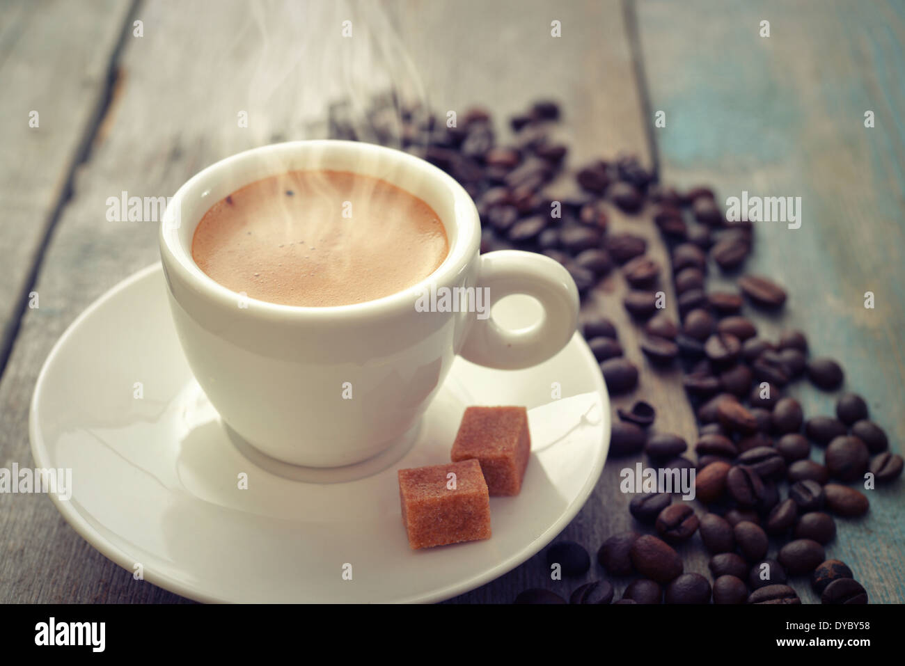 Hot caffè espresso in tazzina con chicchi di caffè su sfondo di legno Foto Stock