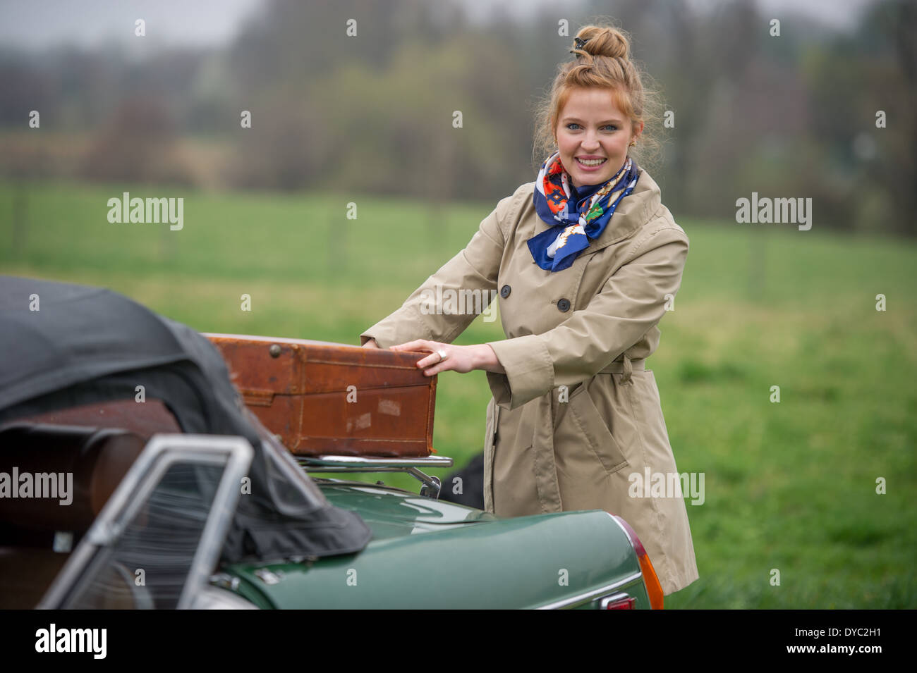 Donna con pranzo sacchi sul viaggio accanto a classic british auto sportiva Foto Stock