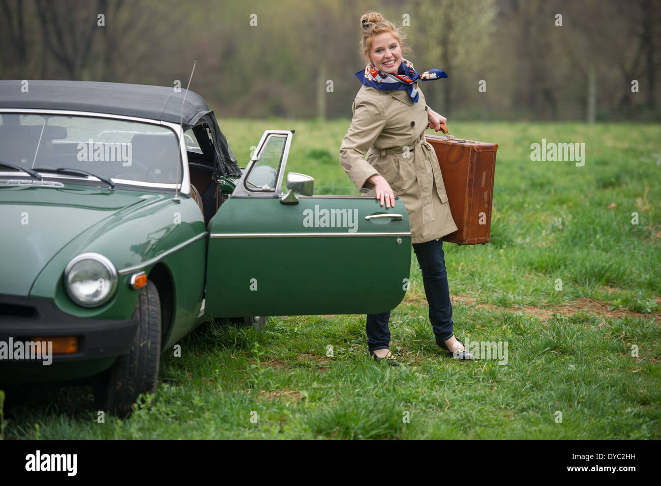 Donna con pranzo sacchi sul viaggio accanto a classic british auto sportiva Foto Stock
