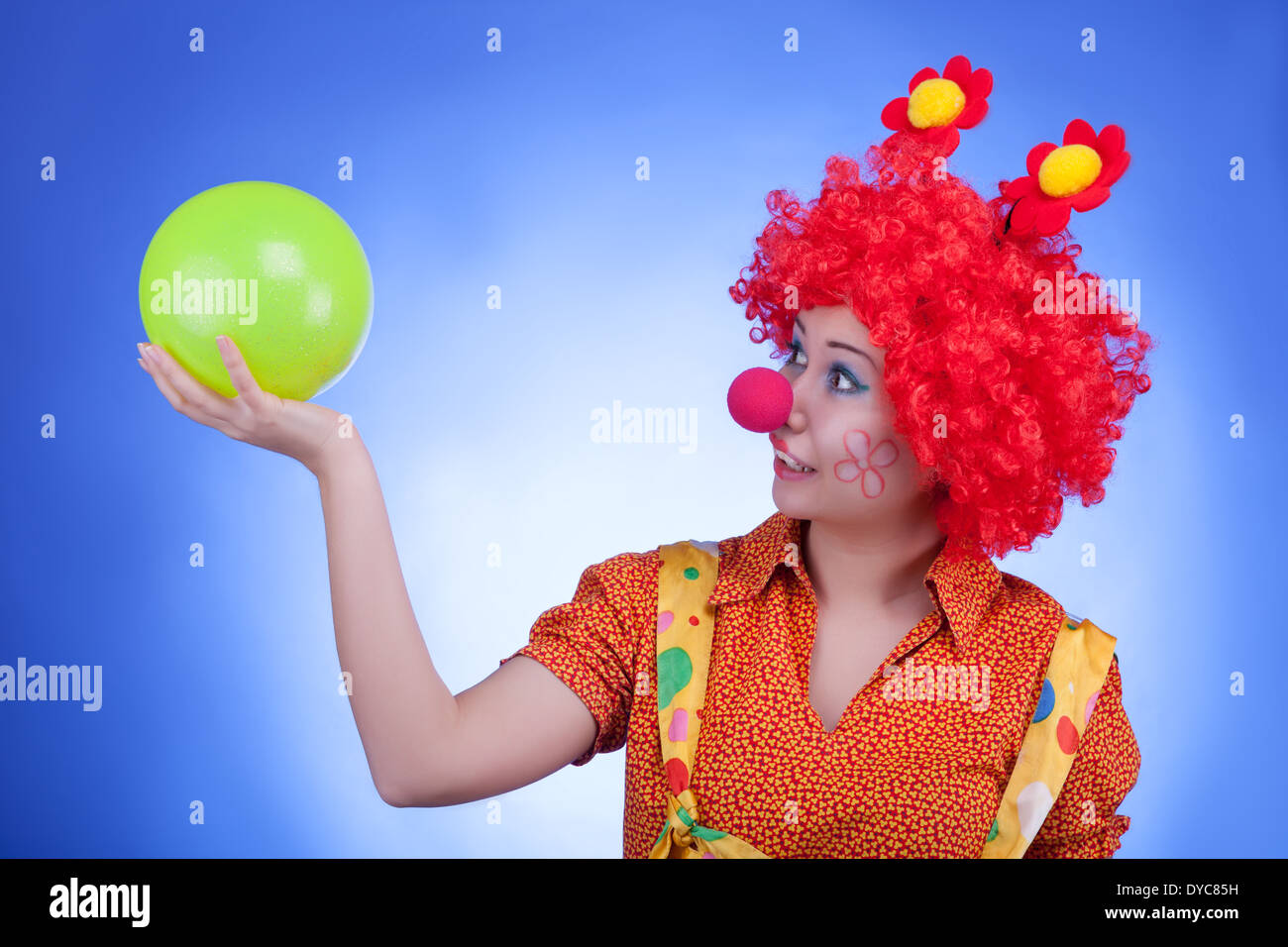 Divertimento donna clown su sfondo blu. Illuminazione da studio Foto Stock
