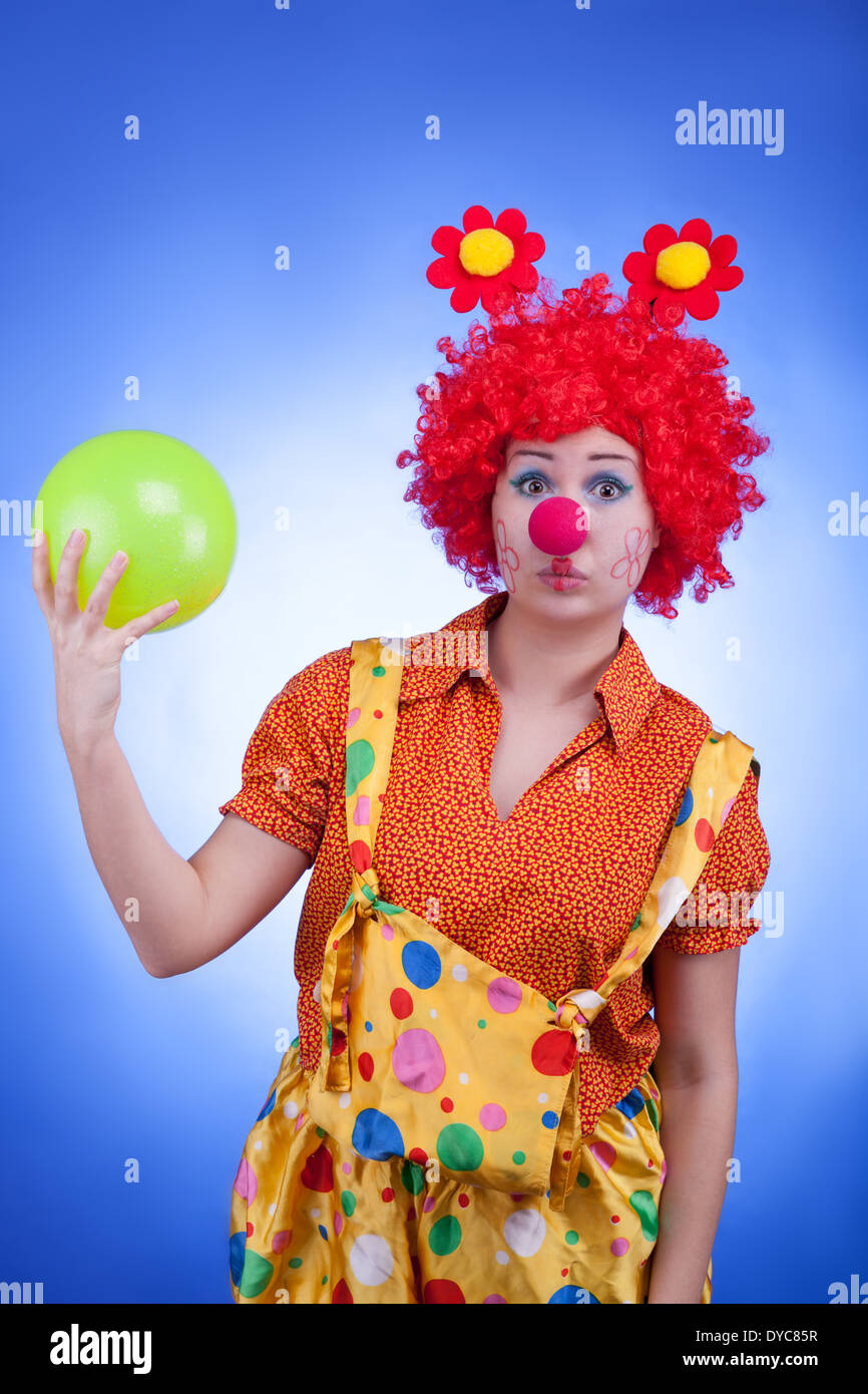 Triste clown con una sfera in mani su sfondo blu. Studio di illuminazione professionale Foto Stock