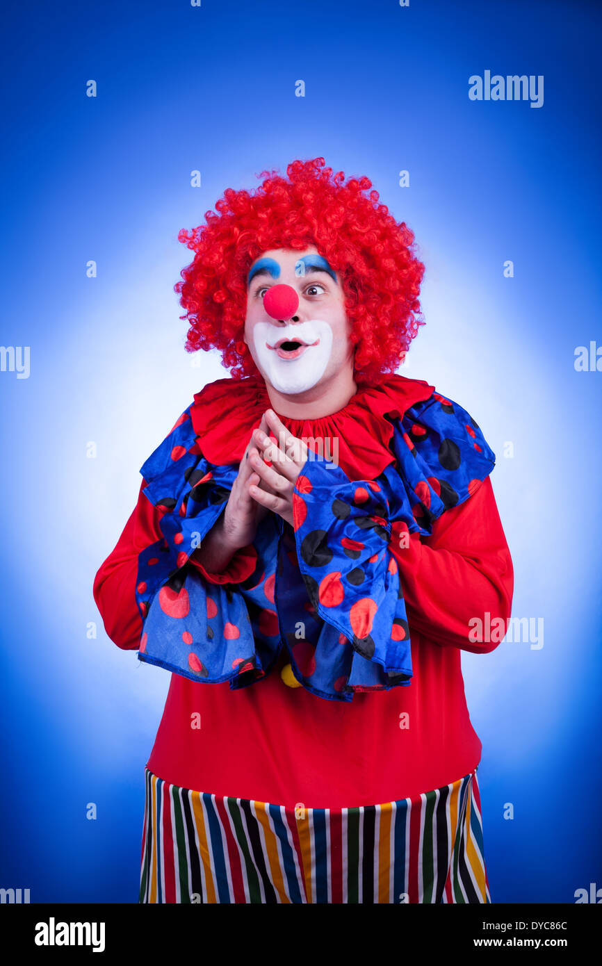 Sorridente clown su sfondo blu studio di ripresa. Illuminazione Professionale Foto Stock