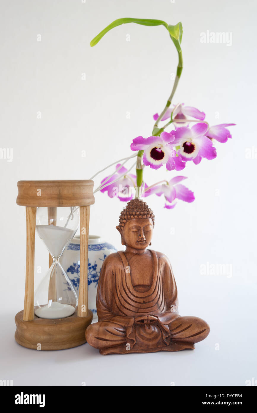 Il Buddha con clessidra e orchidee. Foto Stock