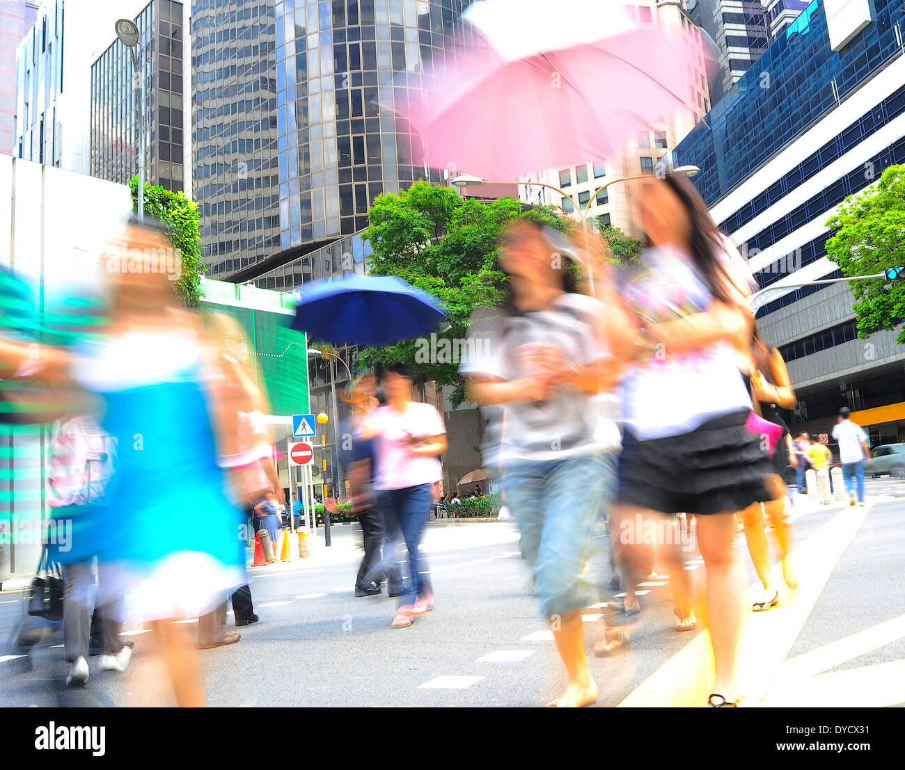 Le donne non identificato con ombrelloni attraversando la strada di Singapore Foto Stock