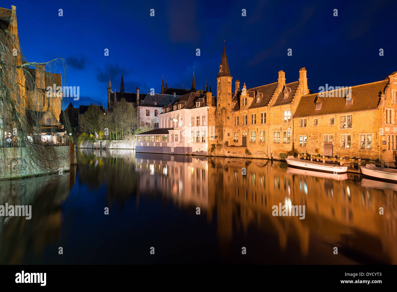 Canali di Bruges di notte Belgio // BRUGES, Belgio - la rete medioevale dei canali di Bruges riflette la luce serale, evidenziando il ruolo storico della città come importante porto commerciale. Conosciuti come la "Venezia del Nord", questi corsi d'acqua una volta collegavano Bruges al Mare del Nord attraverso il canale di Zwin fino alla sua insabbiamento nel XV secolo. I canali conservati si snodano attraverso il sito patrimonio dell'umanità dell'UNESCO, fiancheggiati da edifici secolari che mostrano il patrimonio commerciale della città. Foto Stock