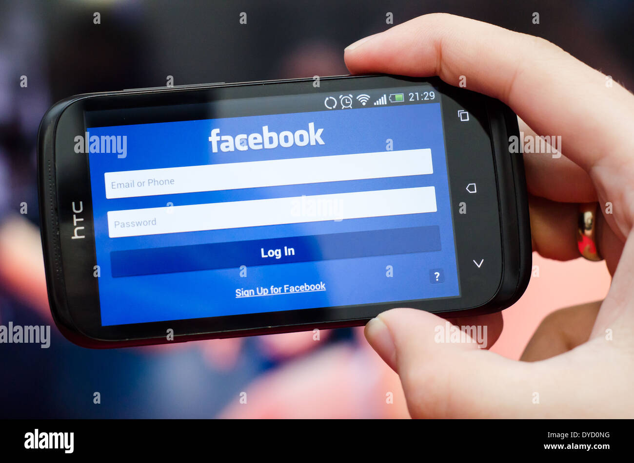 Mano azienda smartphone con il social network Facebook mobile app con interfaccia in inglese Foto Stock