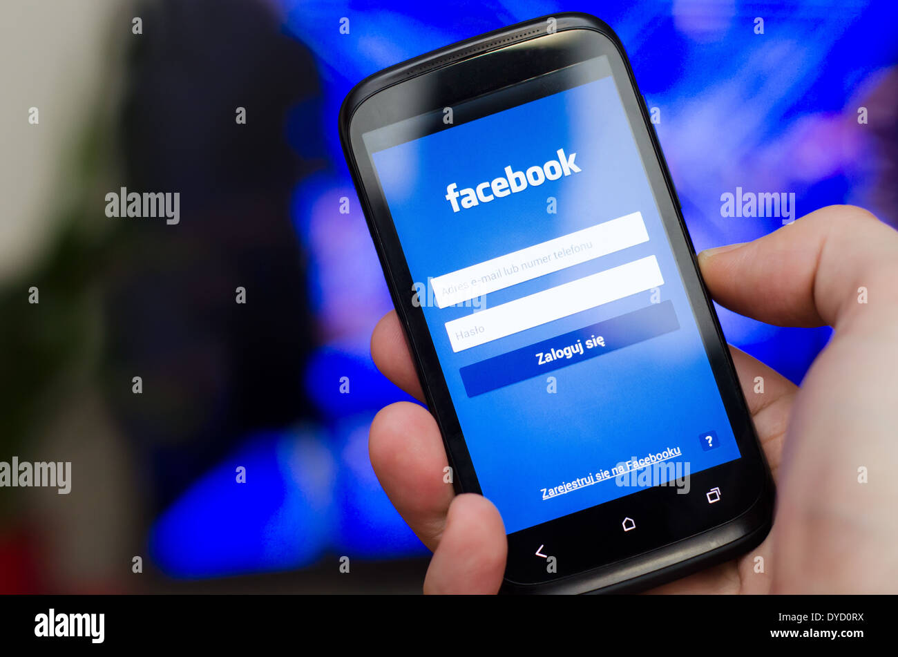 Mano azienda smartphone con il social network Facebook mobile app con interfaccia polacco Foto Stock