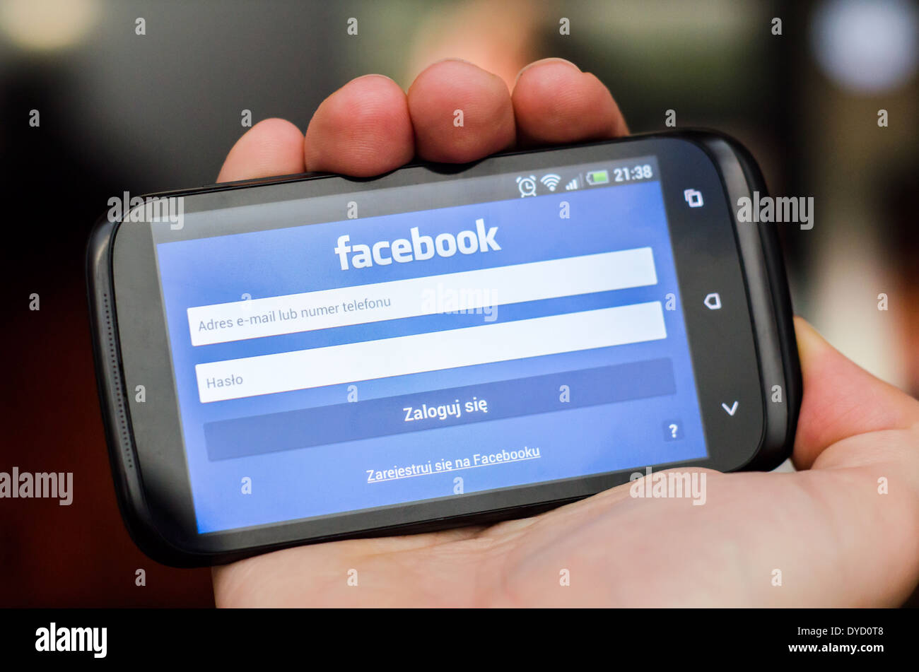 Mano azienda smartphone con il social network Facebook mobile app con interfaccia polacco Foto Stock
