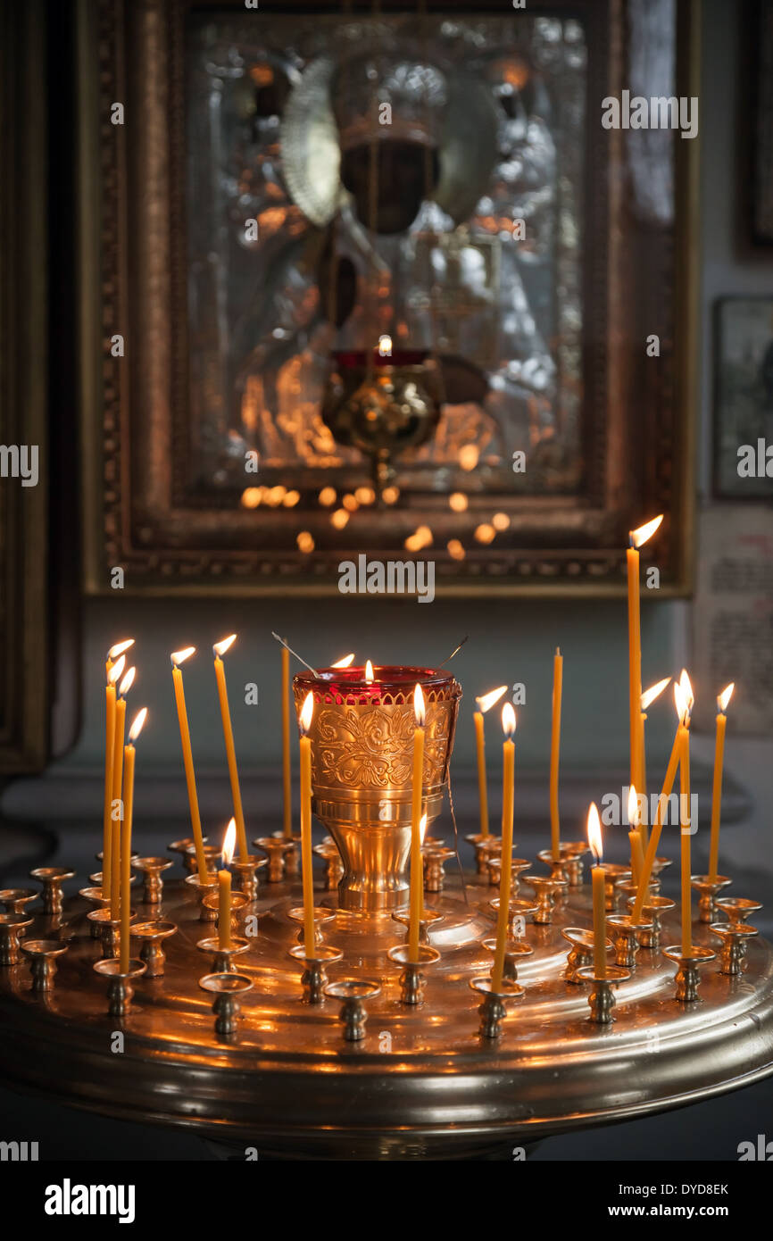 Le candele accese in un buio Chiesa Ortodossa sopra antica icona Foto Stock