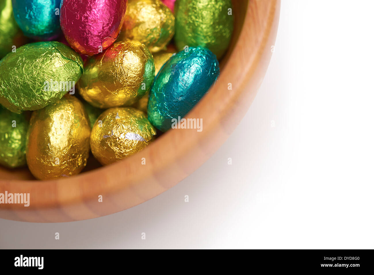 Colouful stagnola avvolto le uova di pasqua in una ciotola su un isolato bianco sullo sfondo. Foto Stock