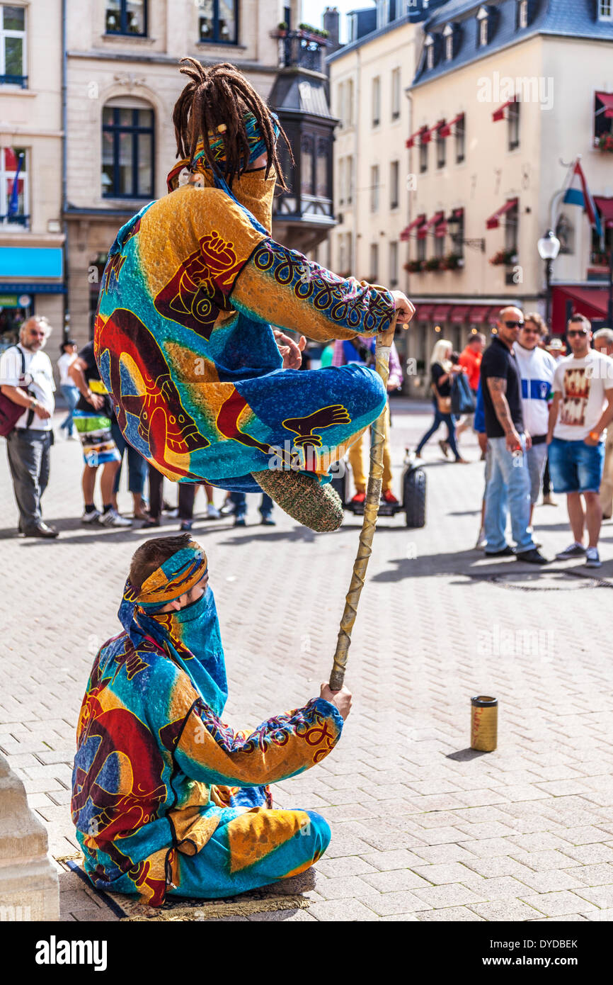 I turisti a guardare due gli artisti di strada di eseguire un trucco di levitazione in Place d'Armes nella città di Lussemburgo. Foto Stock