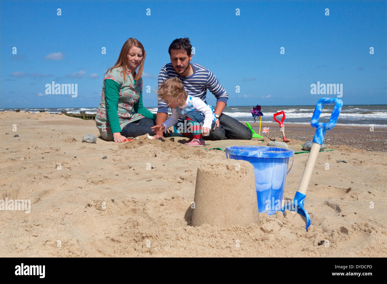 Una giovane famiglia giocando sulla spiaggia a Mundesley in Norfolk. Foto Stock