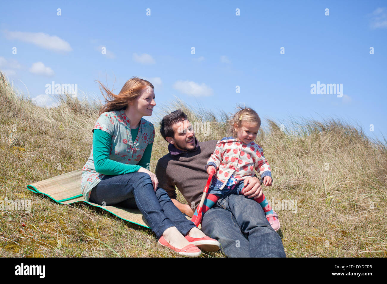 Una giovane famiglia avente il divertimento sulle dune di sabbia a Horsey spiaggia sulla costa di Norfolk. Foto Stock