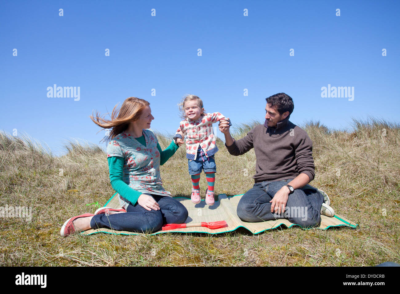 Una giovane famiglia avente il divertimento sulle dune di sabbia a Horsey spiaggia sulla costa di Norfolk. Foto Stock