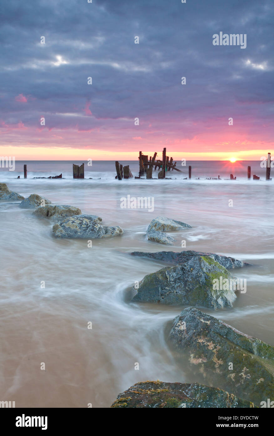 Happisburgh la spiaggia e il mare abbandonati difese a sunrise sulla costa di Norfolk. Foto Stock