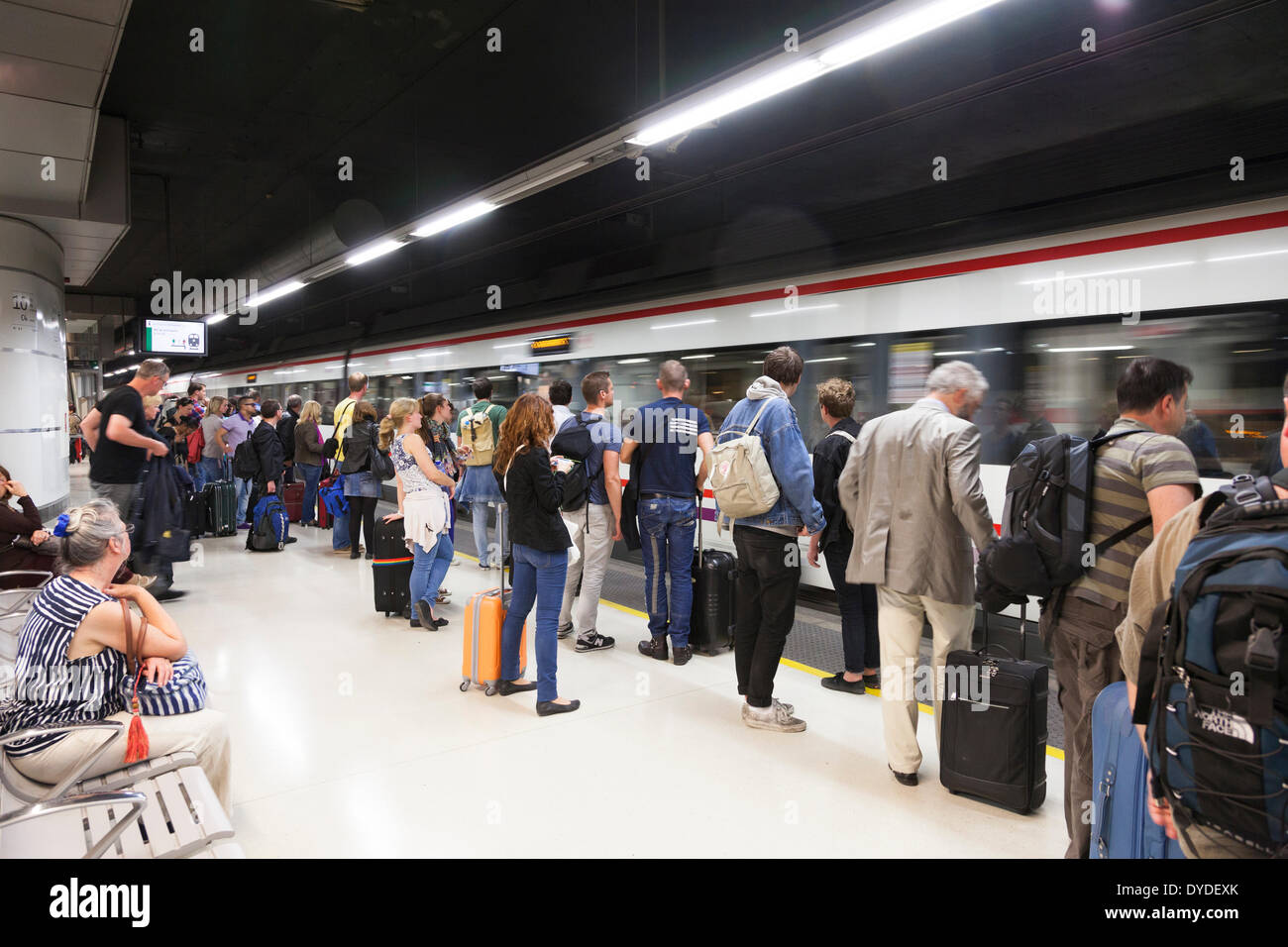 I passeggeri in attesa sulla piattaforma ferroviaria a bordo treno in arrivo. Foto Stock