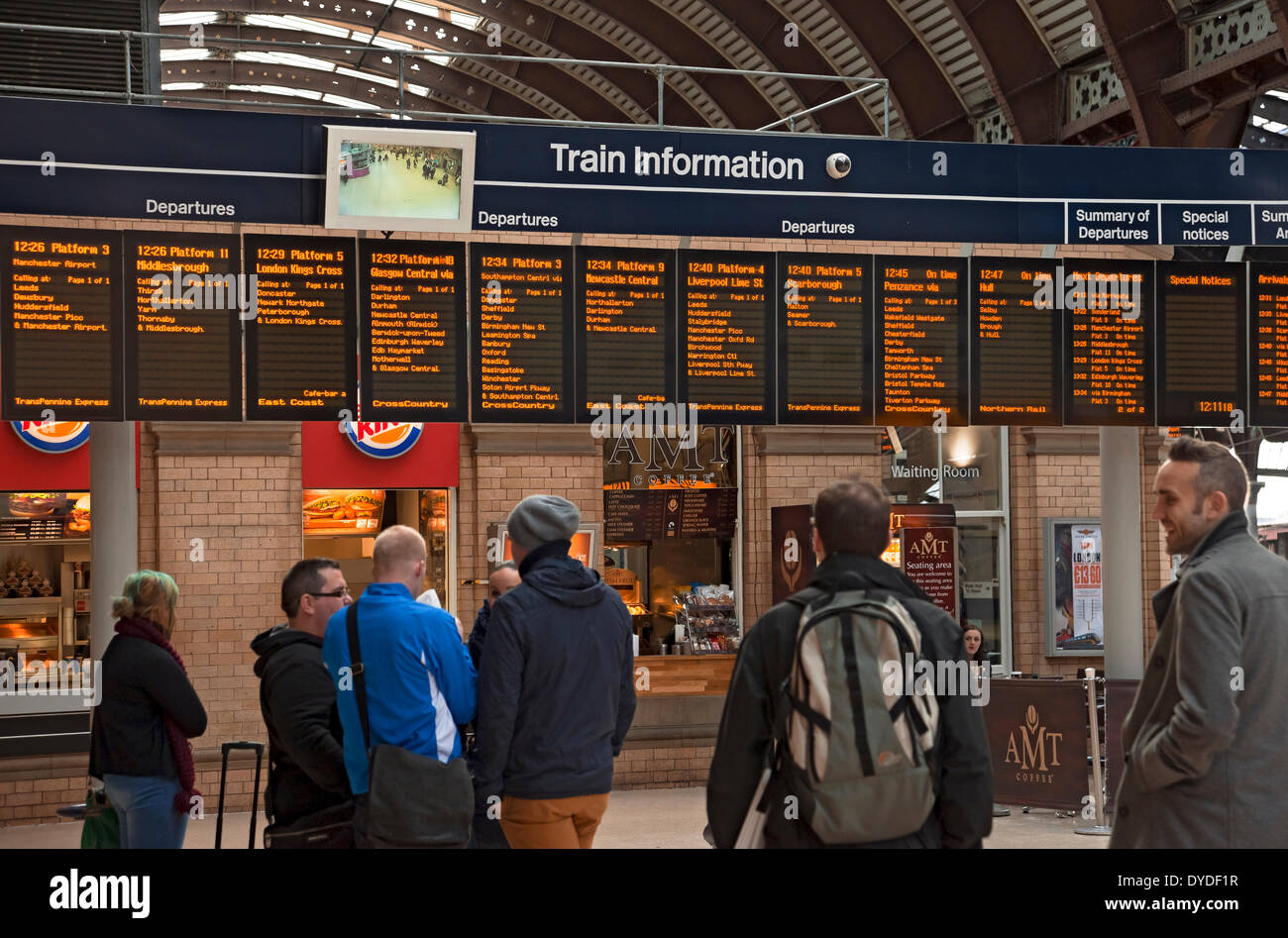 Passeggeri guardando il treno scheda di informazioni alla stazione. Foto Stock