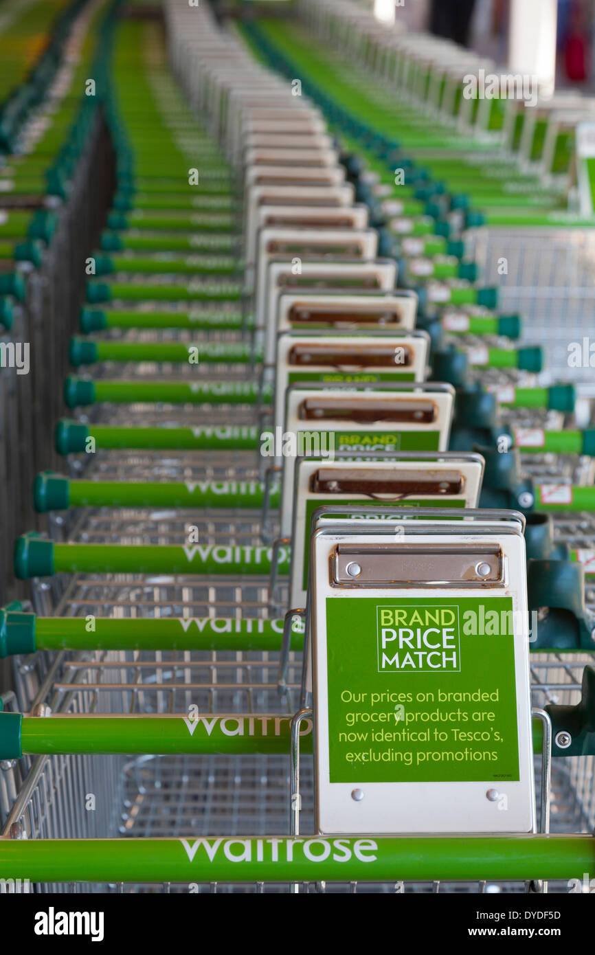 Fila di Waitrose carrelli per supermercati visualizzazione brand price match slogan. Foto Stock