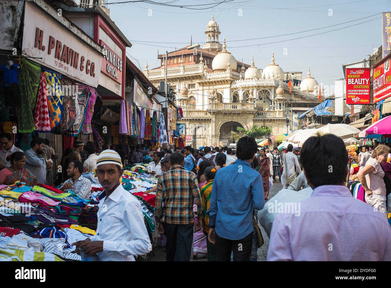 Un giovane uomo musulmano in un mercato di strada con bancarelle che vendono vestiti al di fuori di una grande moschea. Foto Stock