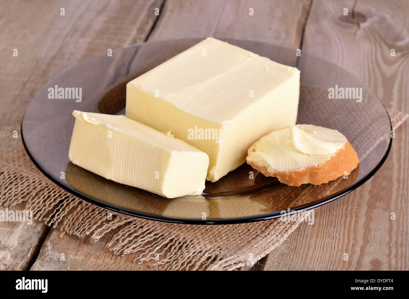 Burro e pane sulla lastra di vetro su un tavolo di legno Foto Stock