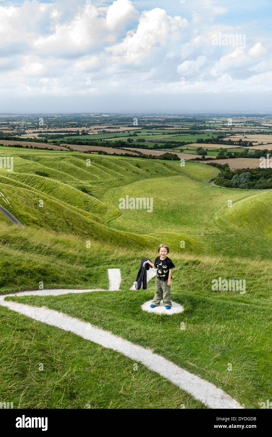 Un giovane ragazzo esplora Uffington White Horse che è un preistorico chalk figura in Oxfordshire. Foto Stock