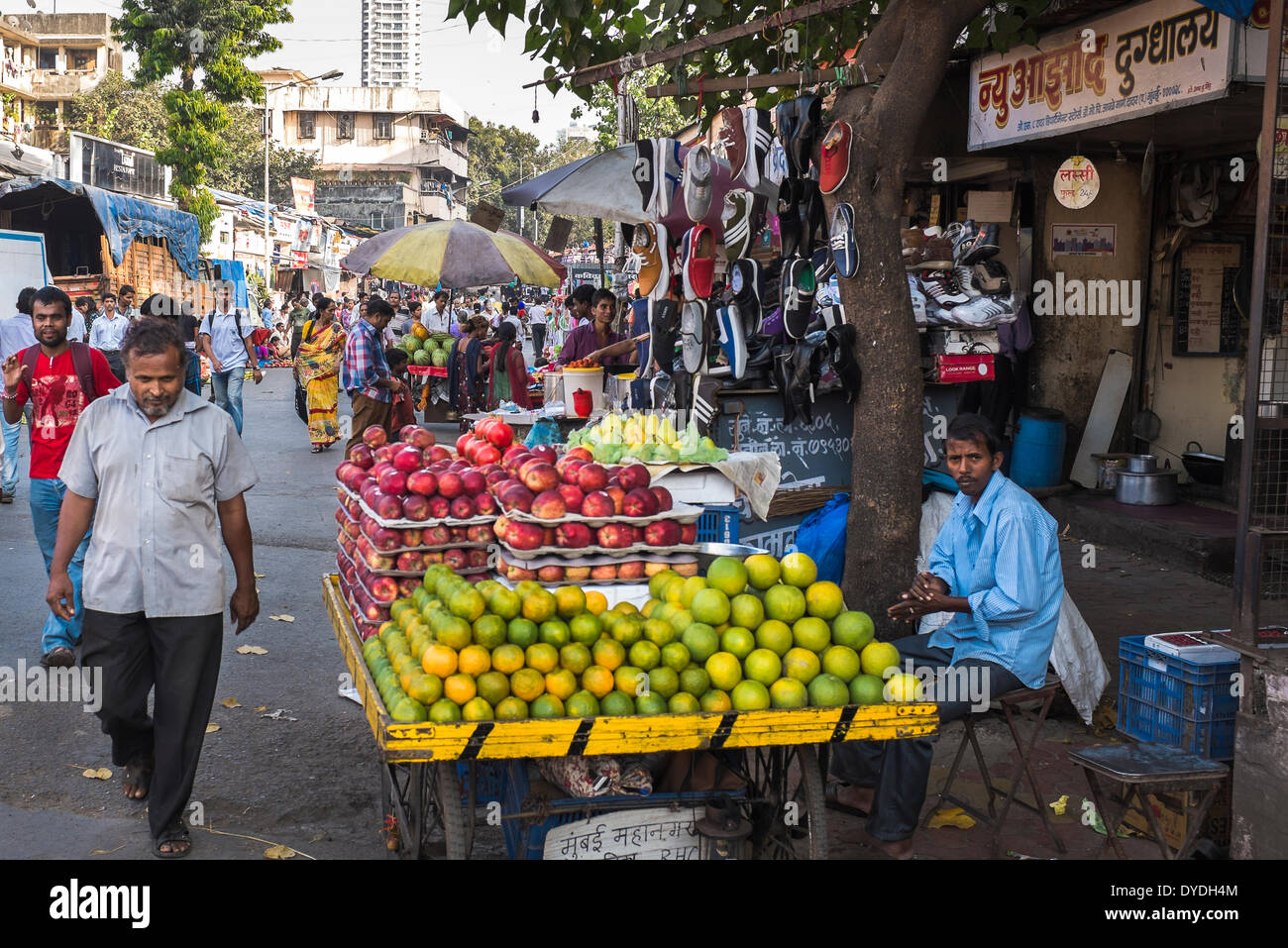 Un fornitore di frutta tendente al suo stallo in una trafficata strada del mercato. Foto Stock