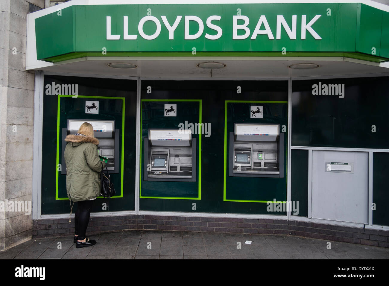 Una donna che utilizza ATM cash point macchine presso una filiale della Banca di Lloyds, Cardiff City Centre Foto Stock