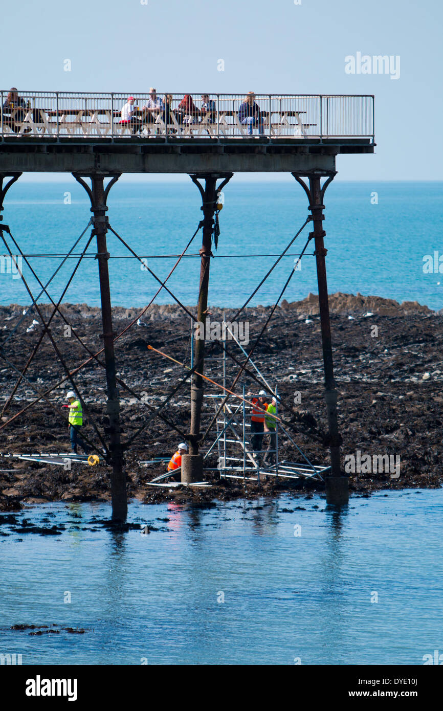 Le riparazioni al molo in Aberystwyth che è stato danneggiato durante le tempeste invernali continuare anche per i vacanzieri godere il sole di Pasqua. Foto Stock