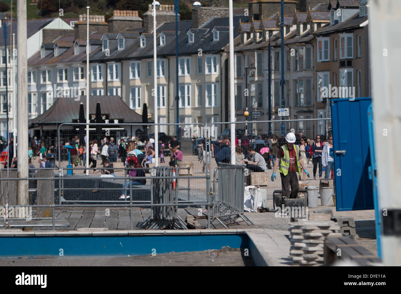 Le riparazioni per il lungomare in Aberystwyth che è stato danneggiato durante le tempeste invernali non è in grado di arrestare le persone che si godono il sole di Pasqua. Foto Stock