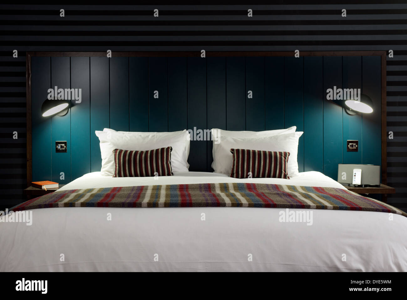 Un confortevole, elegante letto con accessori a righe con una testata blu in una suite presso il Devere Hotel, Swindon, Wiltshire Foto Stock
