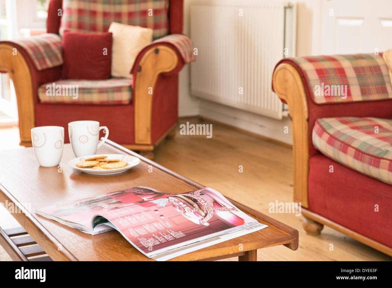 Tazze, biscotti e una rivista su un tavolino in soggiorno Foto Stock