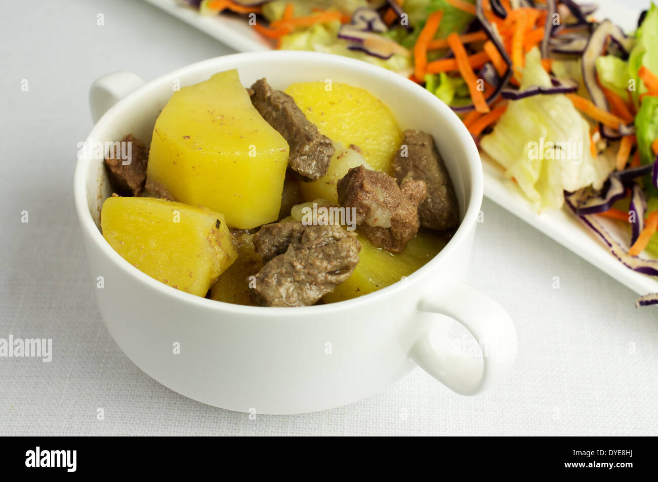 Stufato di manzo con le patate in una zuppiera. Nei pressi di insalata di verdure fresche. Foto Stock