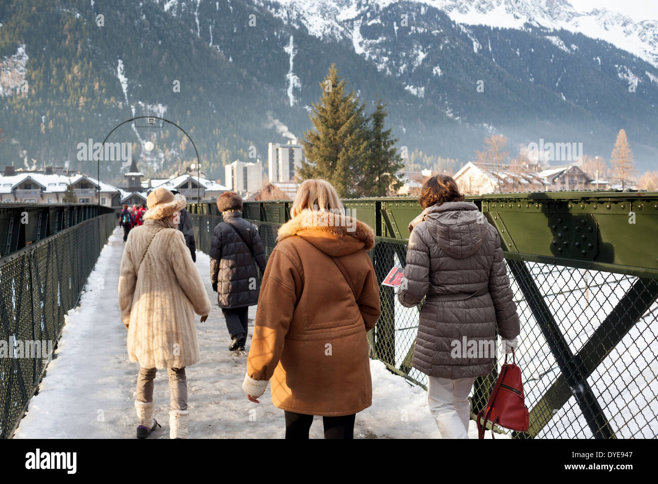 Donne che indossano la pelliccia a piedi attraverso un ponte pedonale nel villaggio di Chamonix Mont Blanc. Foto Stock