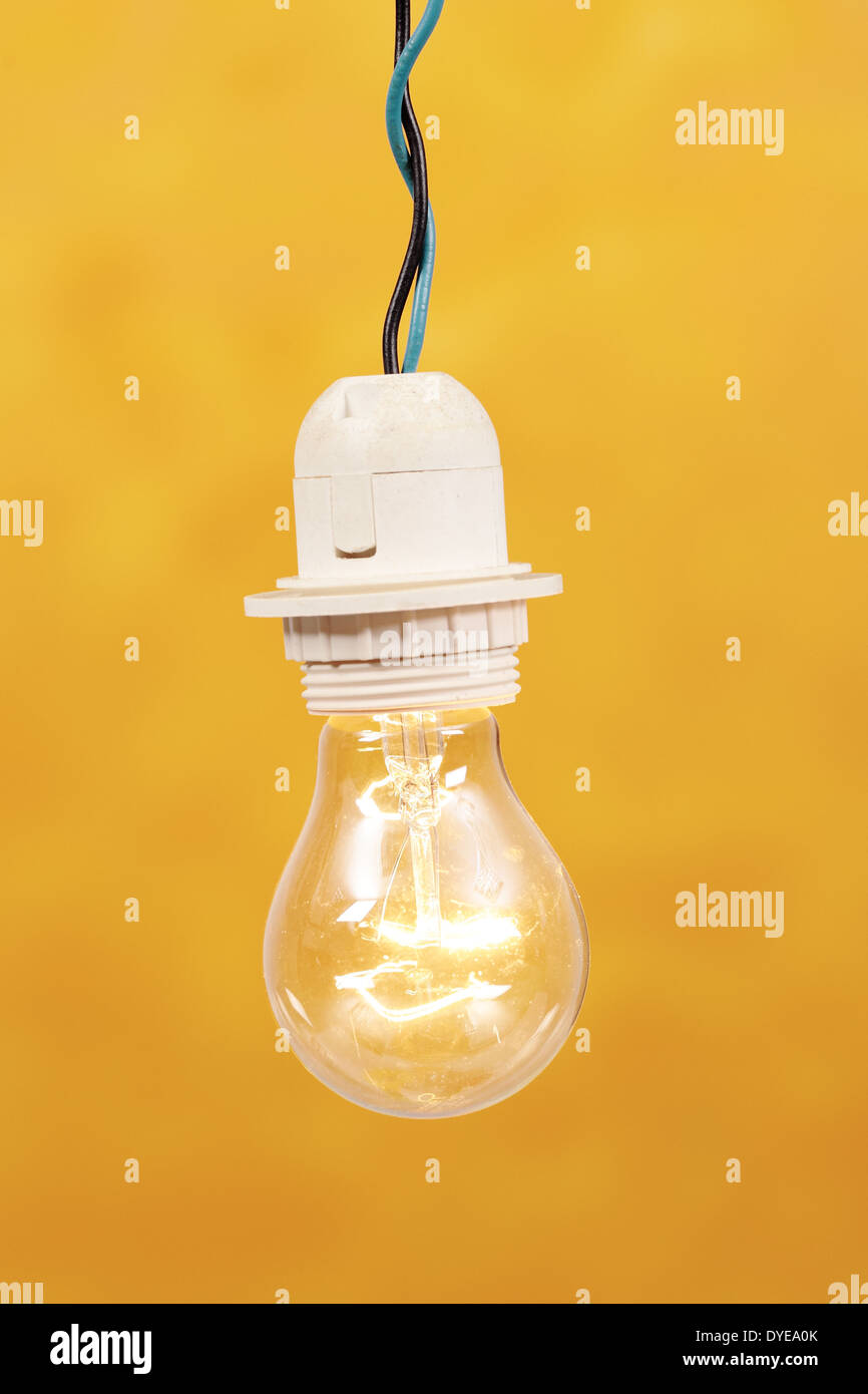 Una lampadina accesa su sfondo giallo Foto Stock
