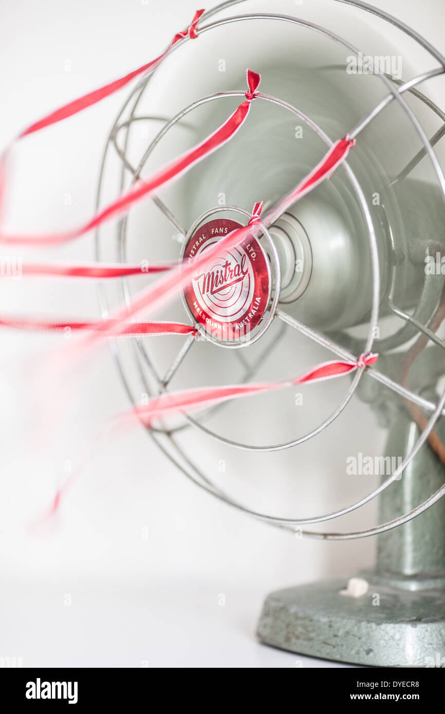 Un vecchio verde Ventilatore da tavolo con nastri di colore rosso su sfondo bianco Foto Stock