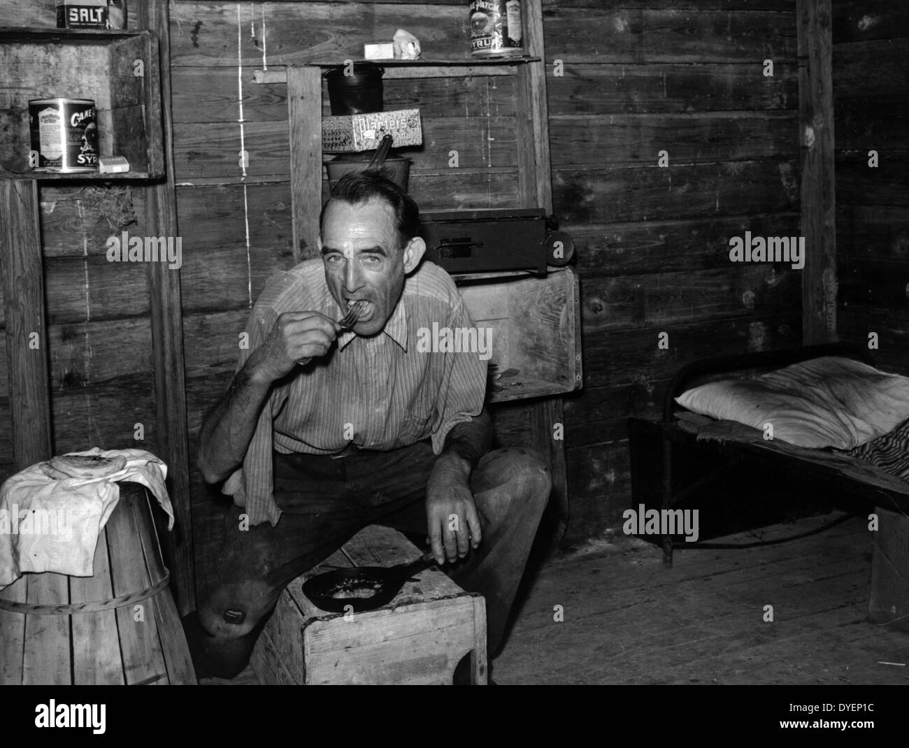 Migrante lavoratore agricolo dal Tennessee, un ex ferrovia uomo, mangiare la cena nella sua baracca, un vecchio strumento house. Homestead, Florida 19390101 Foto Stock