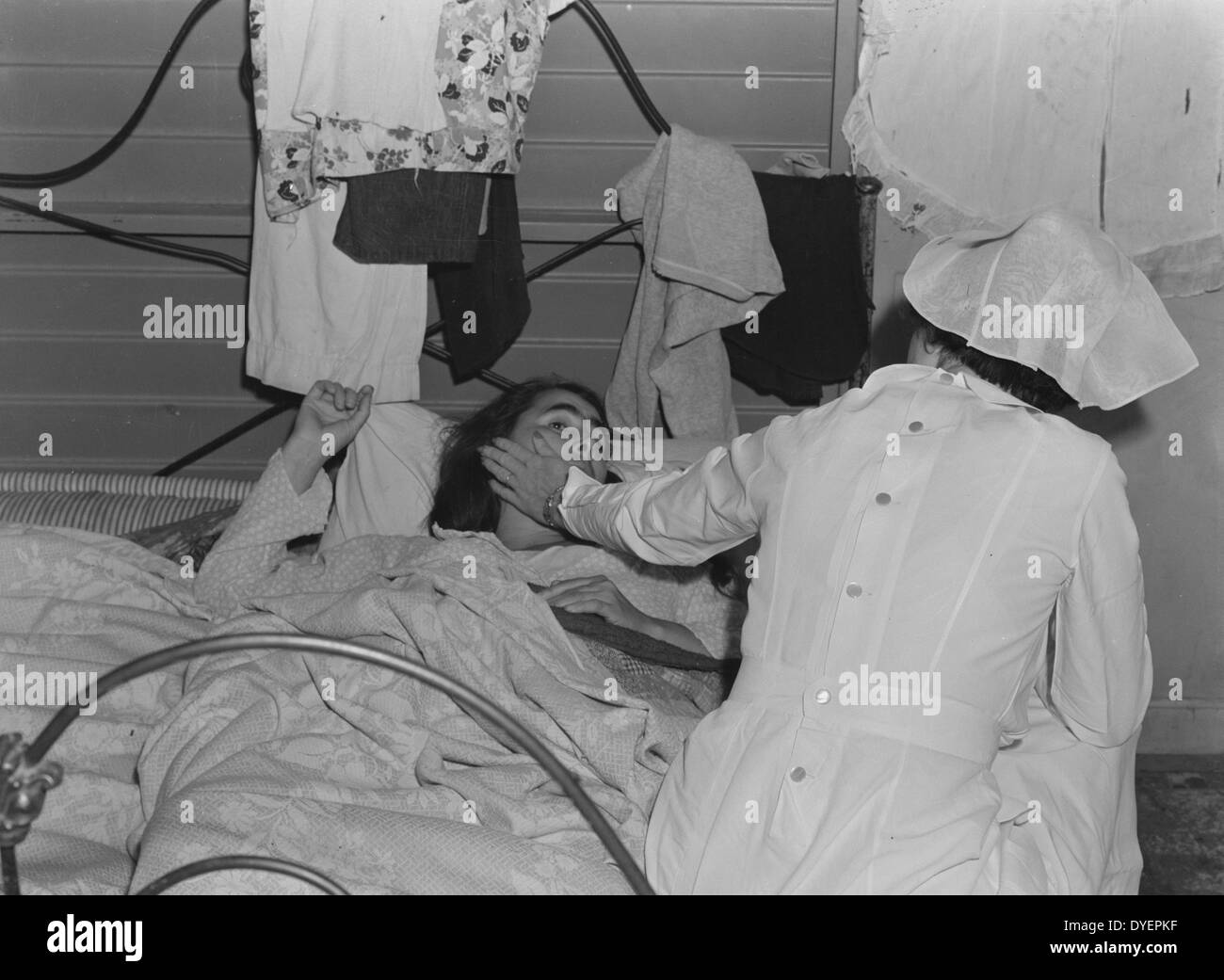 Il Tulare County, California. Farm Security Administration (FSA) camp per flussi migratori di lavoratori agricoli a Farmersville. L'infermiera di prodotti agricoli e la salute dei lavoratori Associazione Medica assiste malati donna migrante in attesa medico da Dorothea Lange 1895-1965, datata 19380101 Foto Stock
