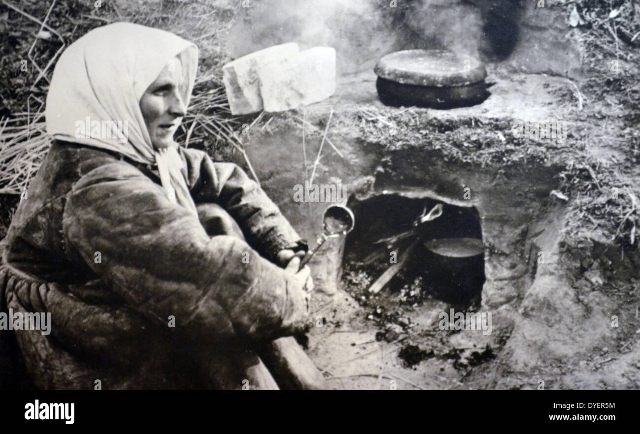 La Seconda Guerra Mondiale: Esercito Tedesco Cartolina che mostra contadina russa donna seduta accanto a un forno di campo come lei fugge l'avanzamento esercito tedesco, 1942 Foto Stock