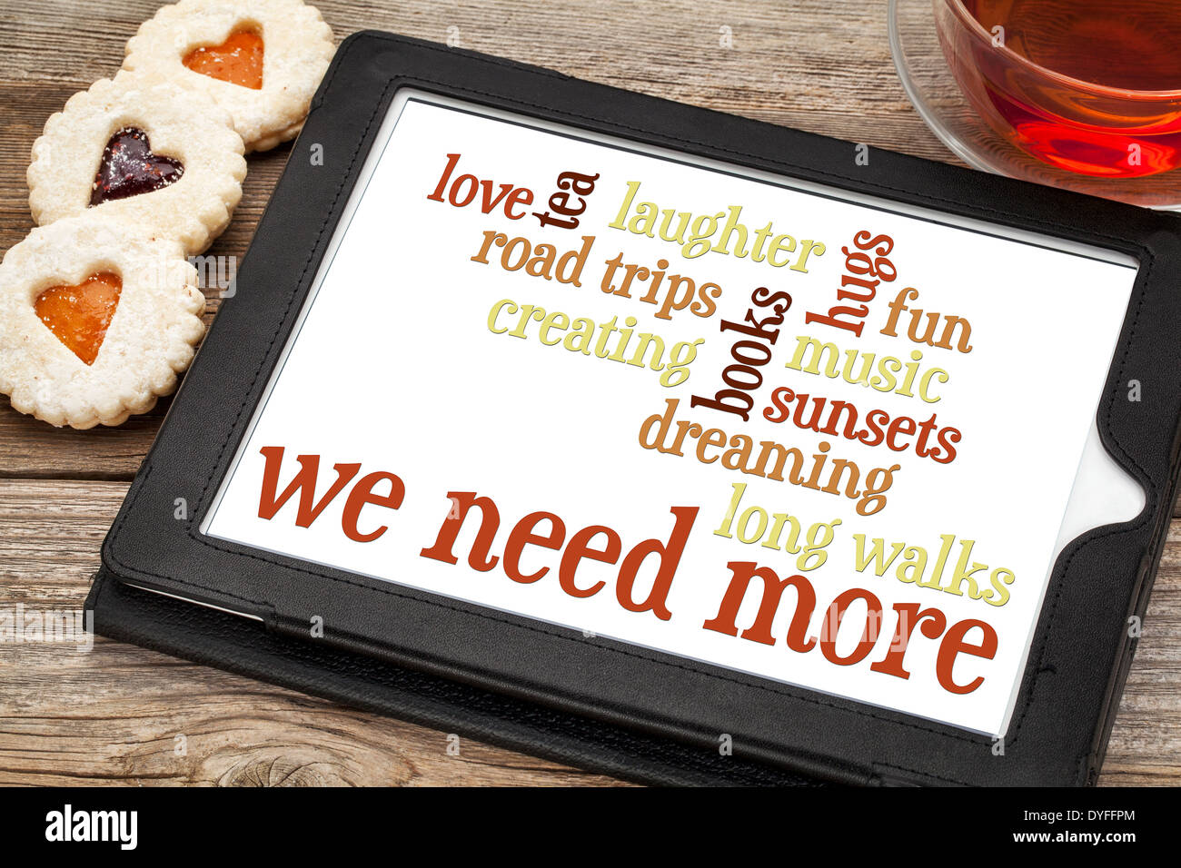 Word cloud su un tanlet digitale con tè e biscotti di cuore - ciò che abbiamo bisogno di più: amore, sognare, musica, tè, creazioni, lunghe passeggiate Foto Stock