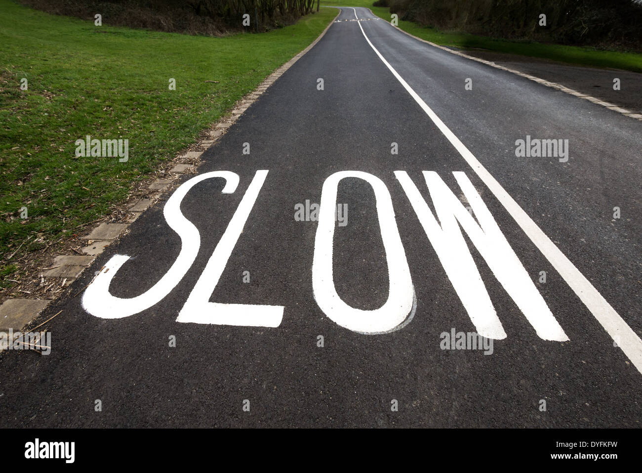 Sign in grassetto lettere bianche su una strada per avvertire gli automobilisti a ridurre la velocità a causa di una piega in avanti. Foto Stock