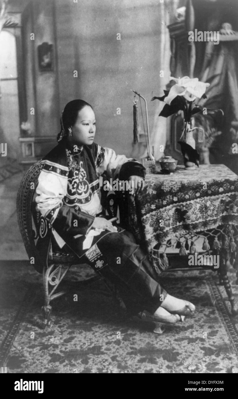 La sig.ra così ho on a piena lunghezza e seduti a tavola di piccole dimensioni, rivolto verso destra in abiti cinesi con pantofole. 1904 Foto Stock