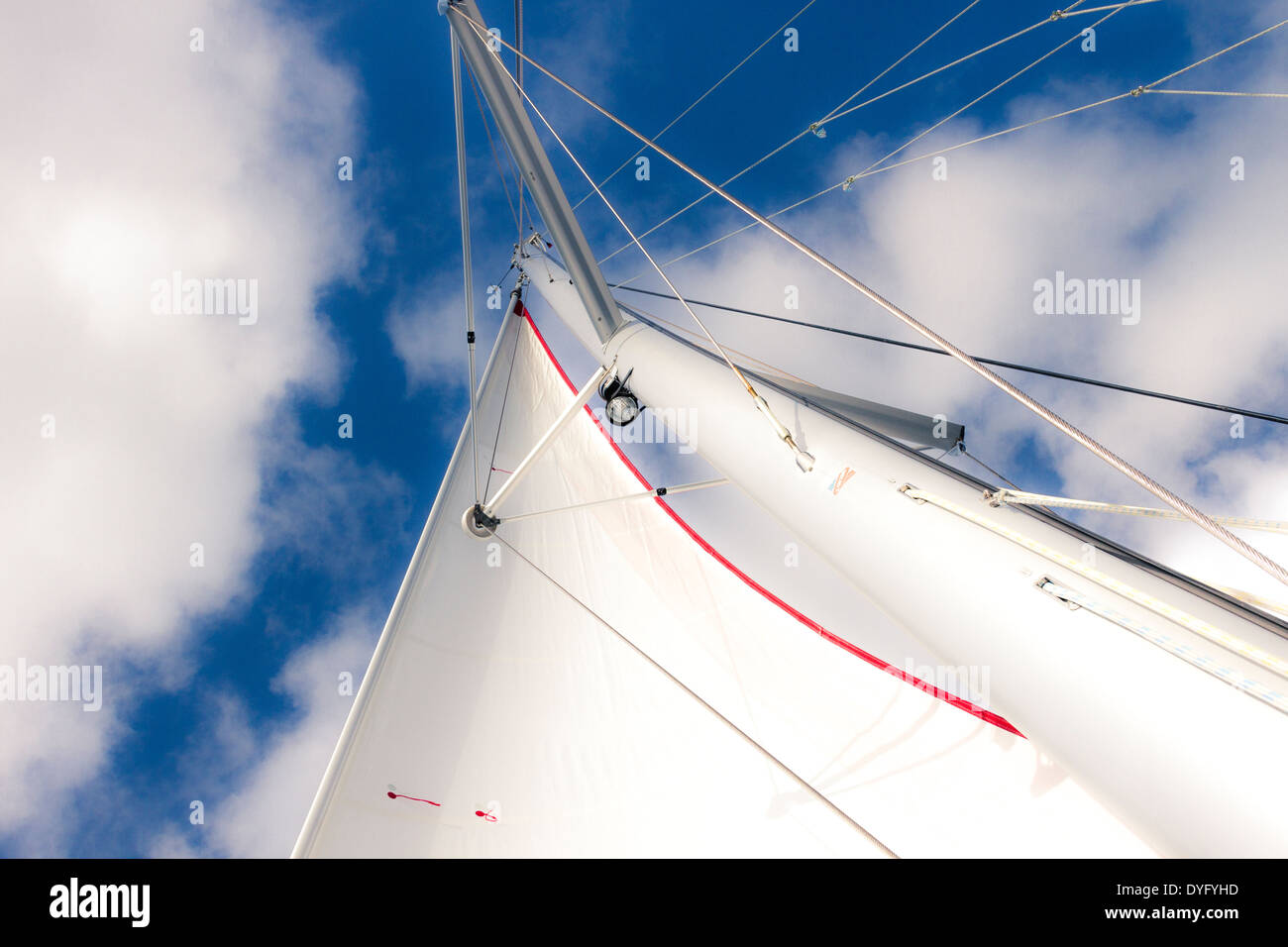 Guardando il vela bianca e il montante di una barca a vela contro un cielo blu con nuvole Foto Stock